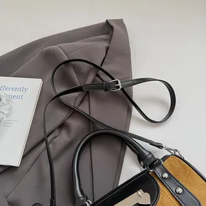 Detailed shot of black leather and ginger suede handbag with rivets and heart charm