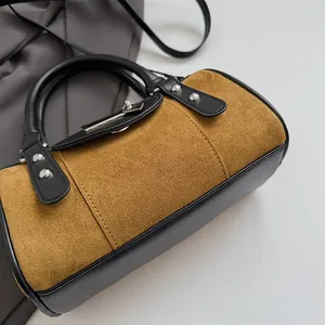 Detail of caramel suede and black leather cylinder bag with silver studs and metal lock