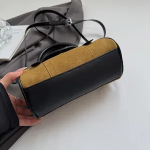 Brown suede and black leather cylindrical Boston bag on a desk with suit jacket
