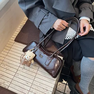 Detaillierte Makroansicht der dunkelbraunen Boston-Tasche mit beigem Plüschbär-Anhänger