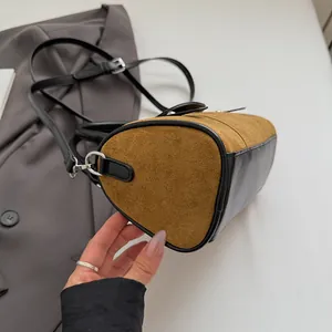 Detail of cylinder handbag featuring brown suede and black leather patchwork with silver hardware