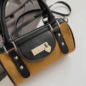 Detail of suede boston bag with silver rivets and heart charm on black leather flap