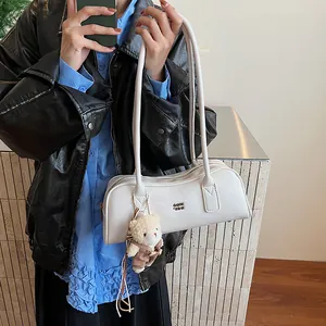 Detail der cremeweißen Boston Bag mit Metall-Logo und süßem Plüschbär-Anhänger