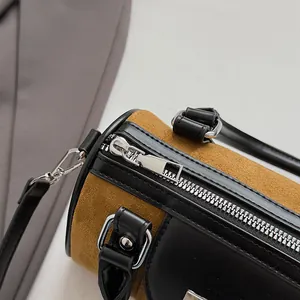 Detail of premium brown suede and black leather patchwork on a cylinder bag with silver zipper