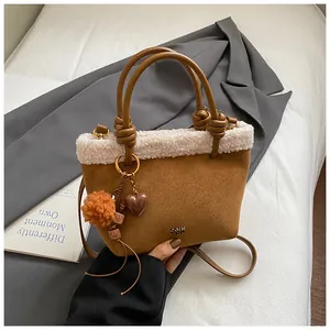 Detailaufnahme der braunen Wildledertasche mit weißem Kunstfellbesatz und Pompon-Anhänger
