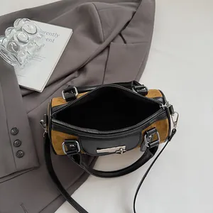 Close-up of brown suede cylinder bag with black leather details and silver metal lock