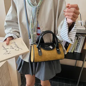 Detail of ginger yellow cylinder handbag with heart pendant lock and adjustable strap