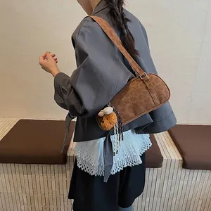 Nahaufnahme der braunen Bowling-Tasche aus Wildleder mit Logo und Teddybär-Anhänger