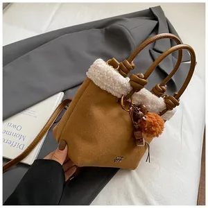 Nahaufnahme der braunen Wildleder-Beuteltasche mit weißem Pelzbesatz und goldenen Metallteilen