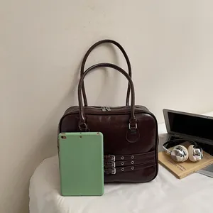 Dettaglio della borsa capiente marrone scuro che contiene un tablet e altri oggetti