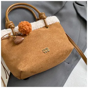Detail der braunen Wildleder-Beuteltasche mit weißem Plüschbesatz und Anhängern