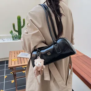 Makroansicht der glänzenden schwarzen Lackleder-Boston-Bag mit Plüschbären-Anhänger