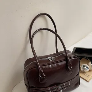 Dettaglio della borsa a spalla in pelle marrone scuro con fibbie e occhielli argento