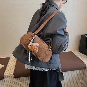 Braune Wildleder-Handtasche mit Plüsch-Hundeanhänger und Flechtriemen auf einer Holztreppe