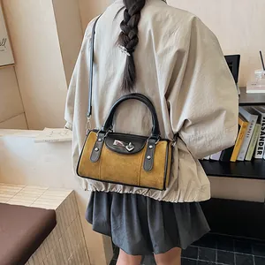 Detail of yellow suede Boston bag with black leather handles and silver lock accent