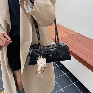 Details der glänzenden schwarzen Boston-Tasche mit Metalllogo und braunem Bärenanhänger
