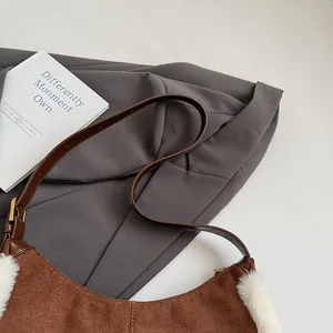 Close-up of brown suede underarm bag featuring white faux fur trim and gold metal zipper