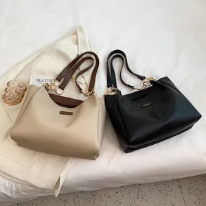 Flat lay of large tote bags in beige and black leather with elegant gold hardware buckles