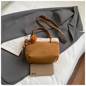 Detailansicht der braunen Wildledertasche mit weißem Pelzbesatz und bunten Anhängern