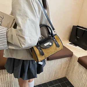 Detail of tan suede and black faux leather cylinder Boston bag with silver heart charm