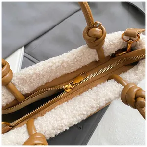 Detail der Lammfell-Verzierung und braunen Ledertasche mit Knotengriff und goldenem Reißverschluss