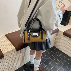 Close-up of a mini yellow cylinder handbag featuring black leather trim and a heart charm