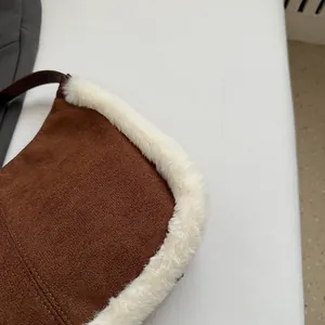 Close-up of brown faux suede texture with soft white plush trim on a shoulder bag