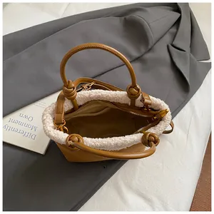 Nahaufnahme der braunen Wildledertasche mit weißem Kunstfellbesatz und Knotengriff