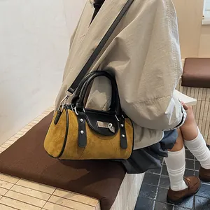 Detail of mustard yellow suede Boston bag with black leather trim and silver heart buckle