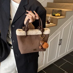 Nahaufnahme der braunen Wildleder-Beuteltasche mit weißem Lammfellbesatz und Herzanhänger