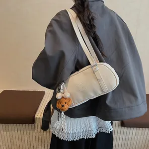 Detail der cremefarbenen Bowling-Tasche mit Markenprägung und Bären-Anhänger