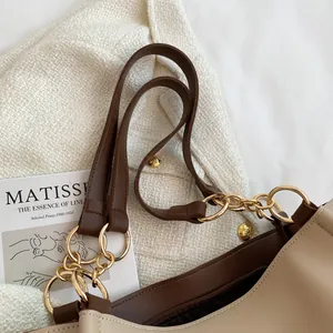 Detail of color-block tote bag with golden chain links and brown leather wide strap