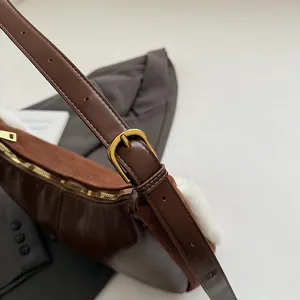 Detail of suede crossbody bag with vintage gold buckle and smooth zipper closure