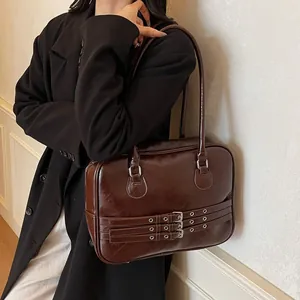 Dettaglio della borsa a spalla in pelle marrone scuro con fibbie vintage e inserti argento