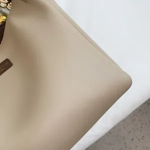 Detailed close-up of light beige lychee pattern leather tote with golden metal hardware