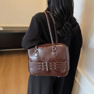 Dettaglio della borsa a spalla marrone vintage con cinturini decorativi con fibbie in metallo