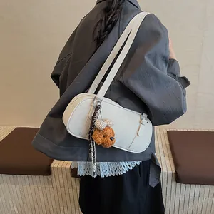 Detailansicht der cremefarbenen Bowlingtasche mit Teddybär-Anhänger und Prägedetail