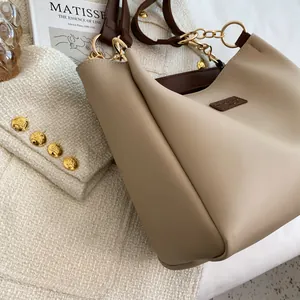 Detail of beige tote bag showing matte leather texture, brown handles and gold hardware