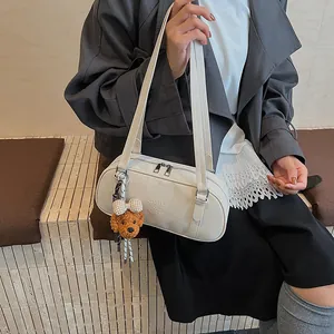 Detail der elfenbeinfarbenen Bowlingtasche mit Logo und braunem Teddy-Anhänger