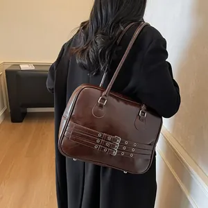 Dettaglio borsa a spalla in pelle marrone scuro con tre fibbie argento e finitura lucida