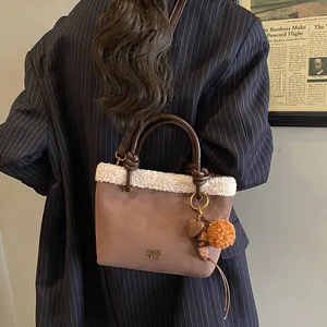 Detail der braunen Wildleder-Beuteltasche mit weißem Plüschbesatz und Herz-Charm-Anhänger