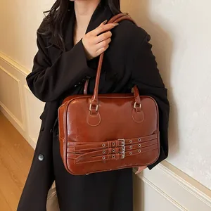 Dettaglio della borsa a spalla marrone con tre cinturini a fibbia in stile retrò