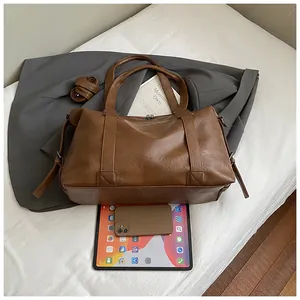 Detail of large brown tote bag with vintage leather texture and removable strap