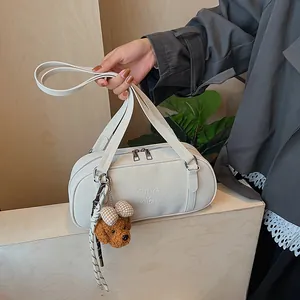 Nahaufnahme der weißen Bowling-Tasche aus Leder mit Markenlogo und Teddybär-Anhänger