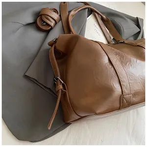 Detail of large brown PU leather travel tote with lychee grain and adjustable shoulder straps