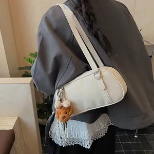 Detail der cremeweißen Bowlingtasche mit Logo-Prägung und süßem Plüsch-Hundeanhänger