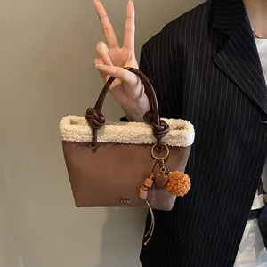Detail der Wildleder-Eimertasche mit weißem Kunstfellbesatz und dekorativen Anhängern