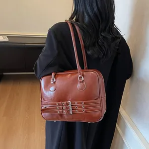 Borsa a spalla retrò marrone con fibbie argentate indossata da una modella in interno