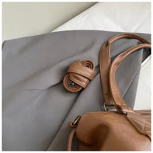 Close-up of vintage brown leather travel tote with detachable shoulder strap and stitching