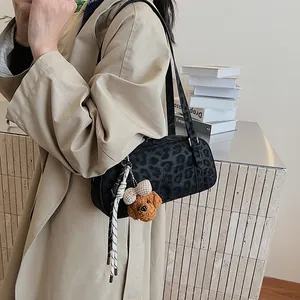 Detail der schwarzen Baguette-Tasche mit Leopardenmuster und Teddybär-Anhänger am Trenchcoat